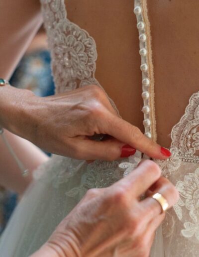 Dettaglio sartoriale della schiena dell'abito da sposa di Sara, arricchito da preziosi bottoncini e pizzo floreale.