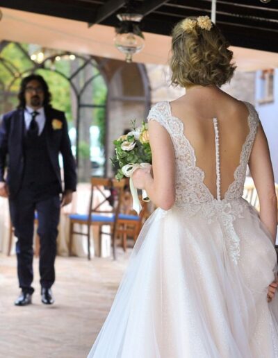 Primo piano della schiena dell'abito da sposa di Sara con eleganti bottoncini e pizzo ricamato.